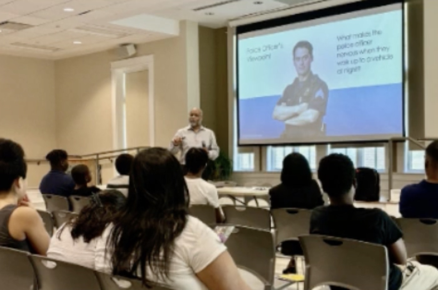 A facilitator presents a Traffic Stop Bootcamp slide to a seated group in a community room.